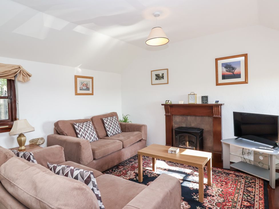 A living room with sofas, a coffee table, and a tv at The Dairy in Common Moor near Liskeard