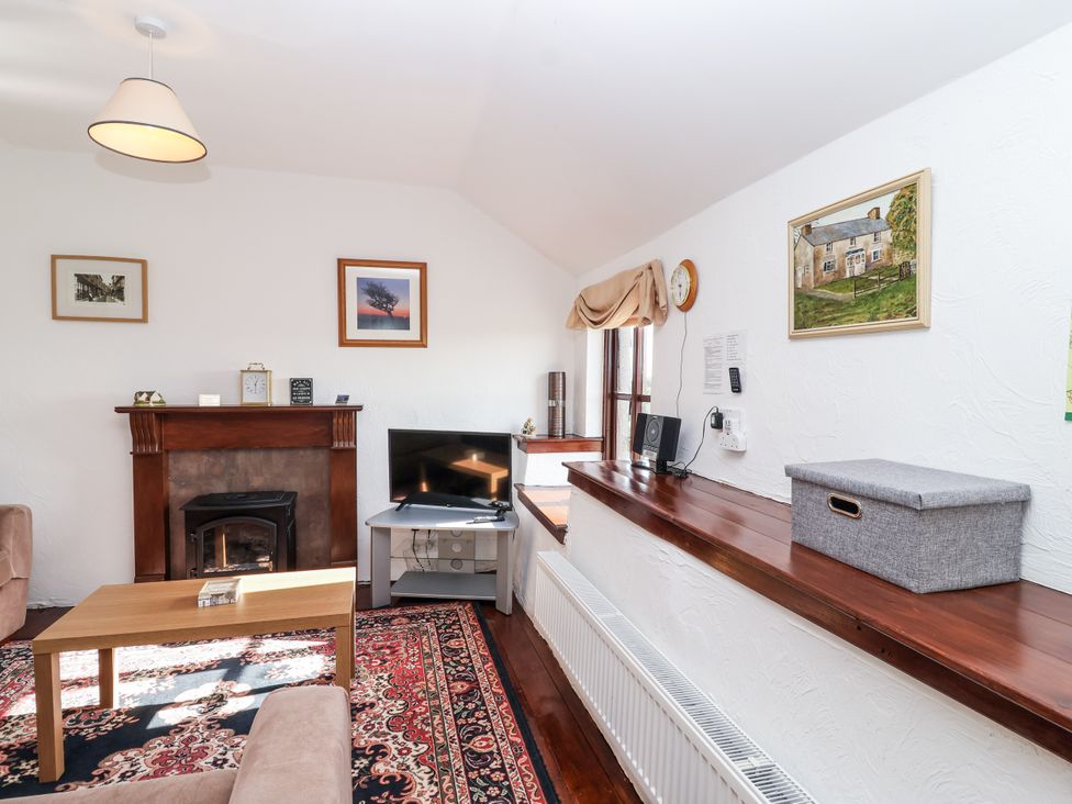 A living room with a fireplace and television at The Dairy in Common Moor near Liskeard