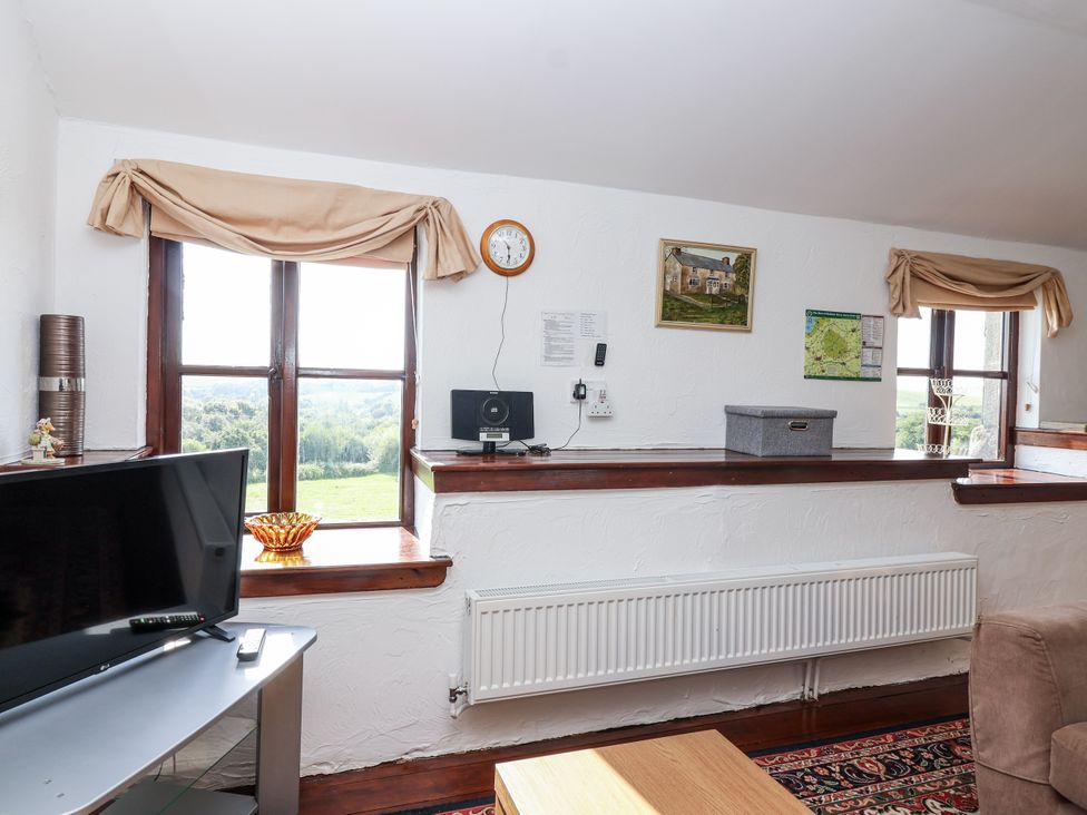 A living room with a television and clock at The Dairy in Common Moor near Liskeard