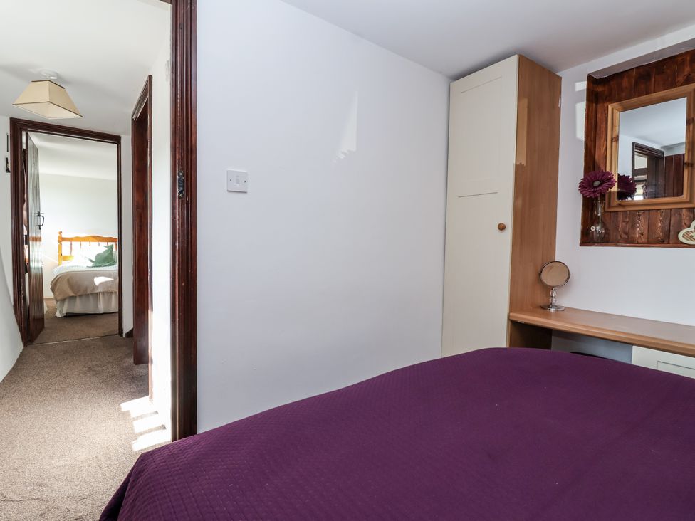 A bedroom with a door leading to another room at The Dairy in Common Moor near Liskeard