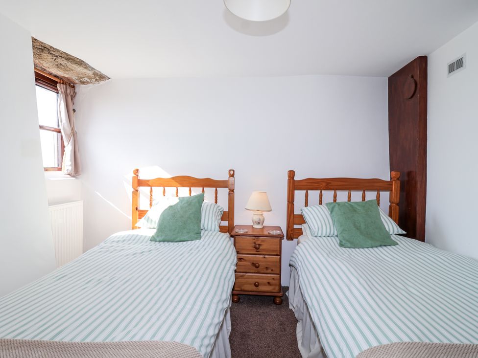 A bedroom with two single beds and a nightstand at The Dairy Common Moor near Liskeard