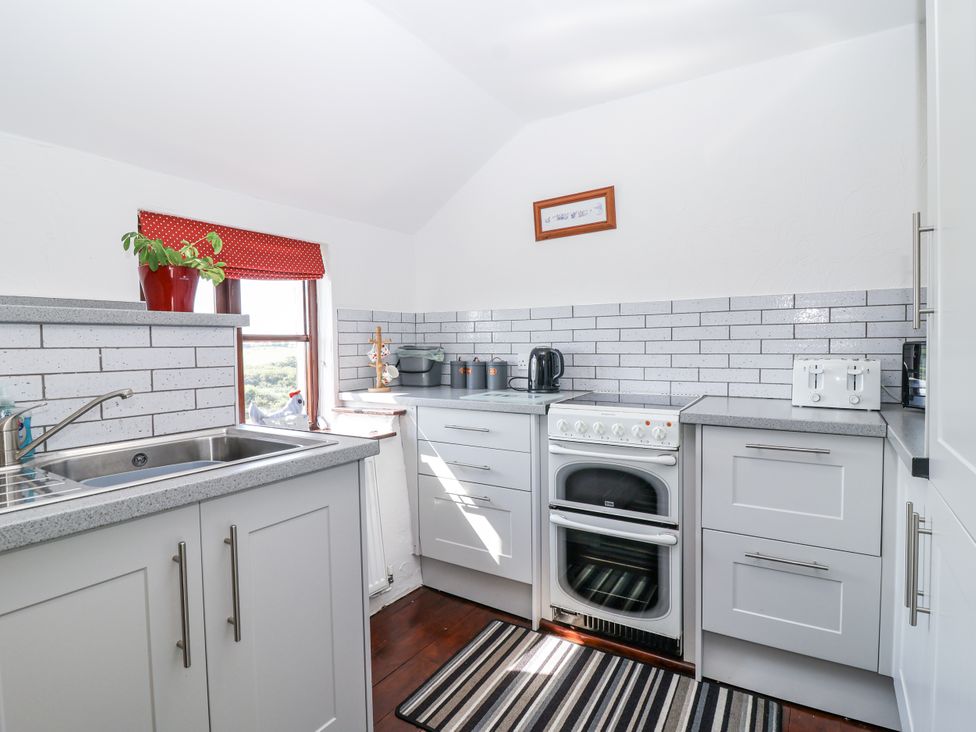 A kitchen with sink, window, plant, kettle, and cooker at The Byre Common Moor near Liskeard