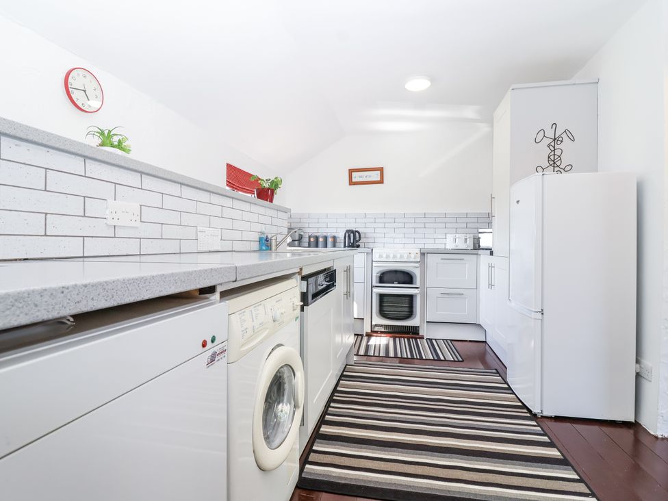 A kitchen with appliances and a striped rug at The Byre in Common Moor near Liskeard