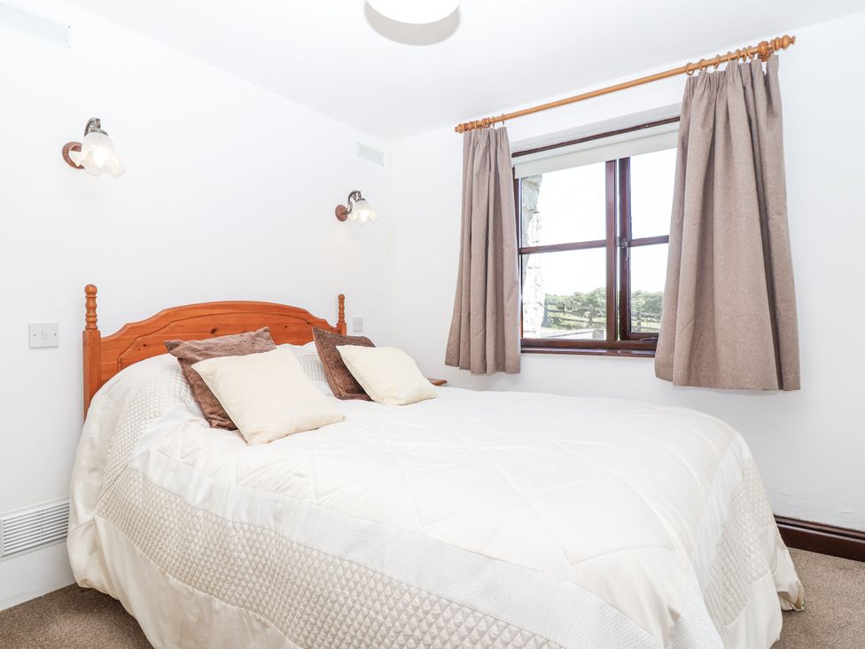 A bedroom with a bed and a window at The Byre in Common Moor near Liskeard