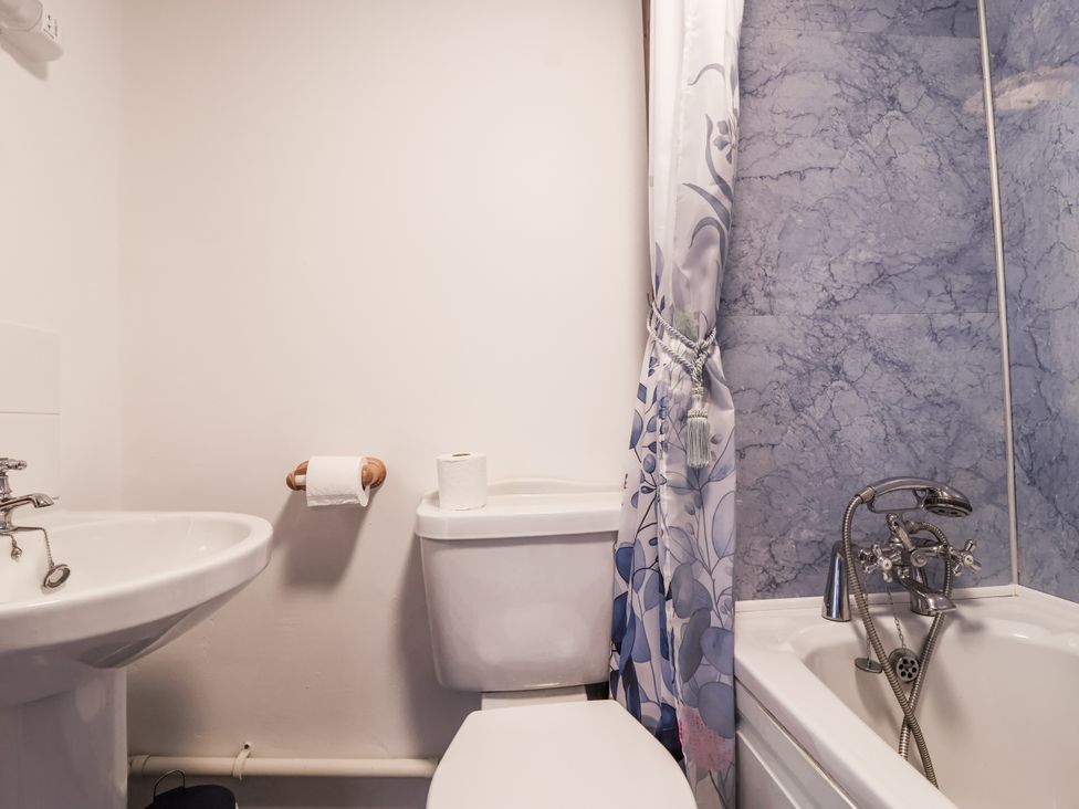A bathroom featuring a sink, toilet, and bathtub with a shower curtain at The Byre in Common Moor near Liskeard
