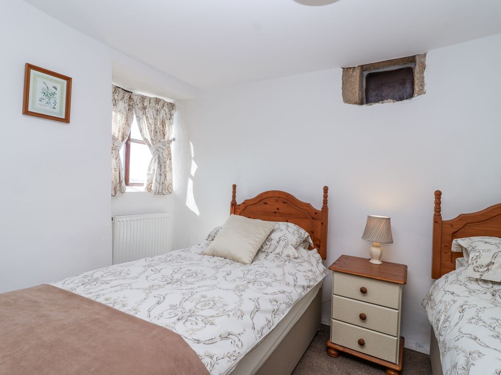 A bedroom with two single beds and a bedside table at The Byre in Common Moor near Liskeard