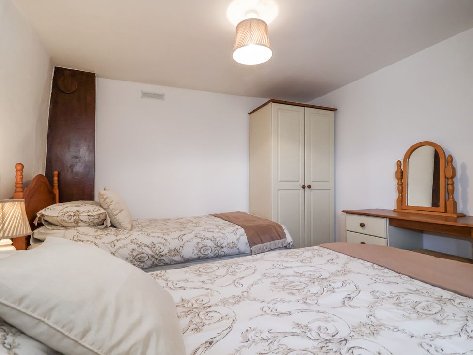 A bedroom with two beds and a wardrobe at The Byre Common Moor near Liskeard