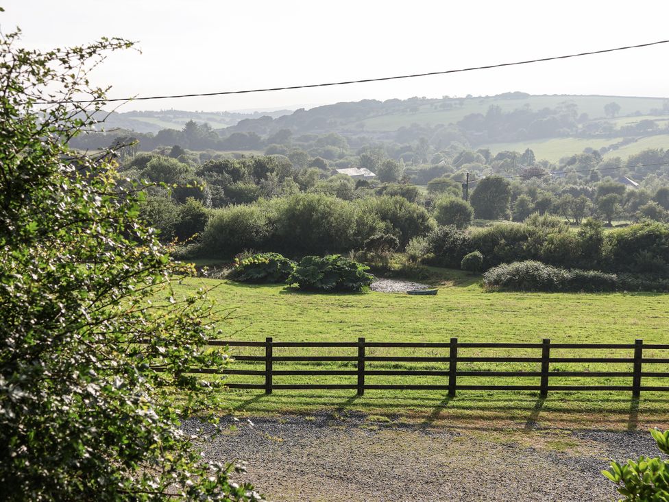 A view of a grassy area with trees and hills at The Byre in Common Moor near Liskeard