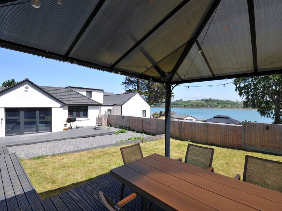 An outdoor area with a table and chairs overlooking water at The Mooring in Northam