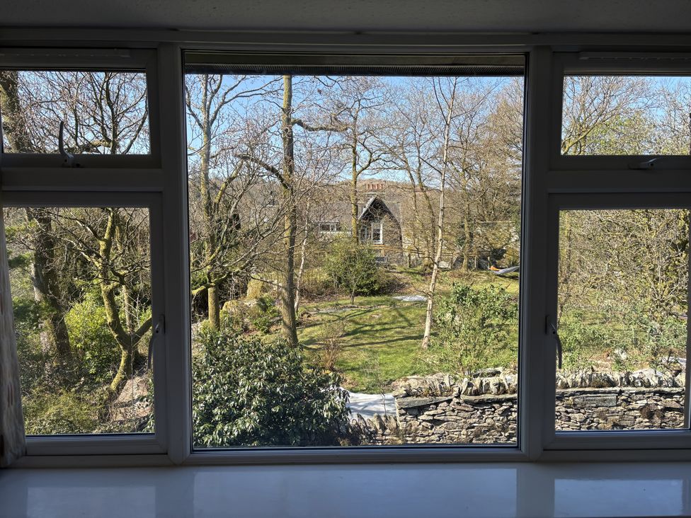 An outdoor view through a window with trees and a building at Rothay Cottage in Ambleside