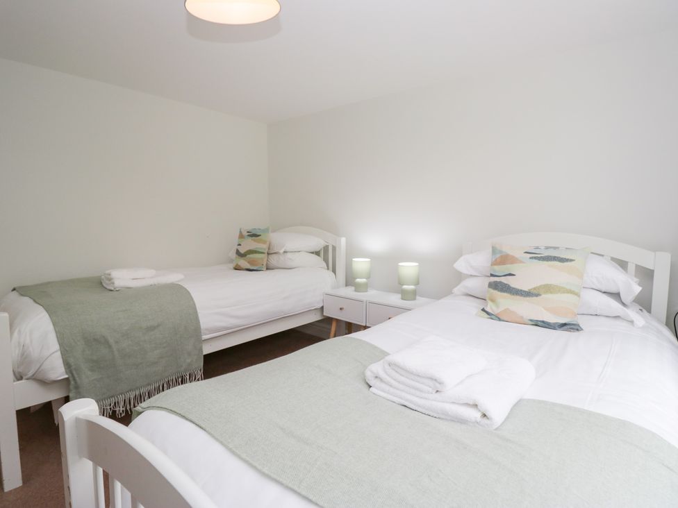 A bedroom with two beds and bedside tables at Rothay Cottage in Ambleside