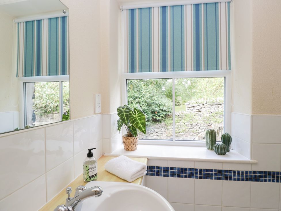 A bathroom with a sink and plants on a windowsill at Rothay Cottage in Ambleside