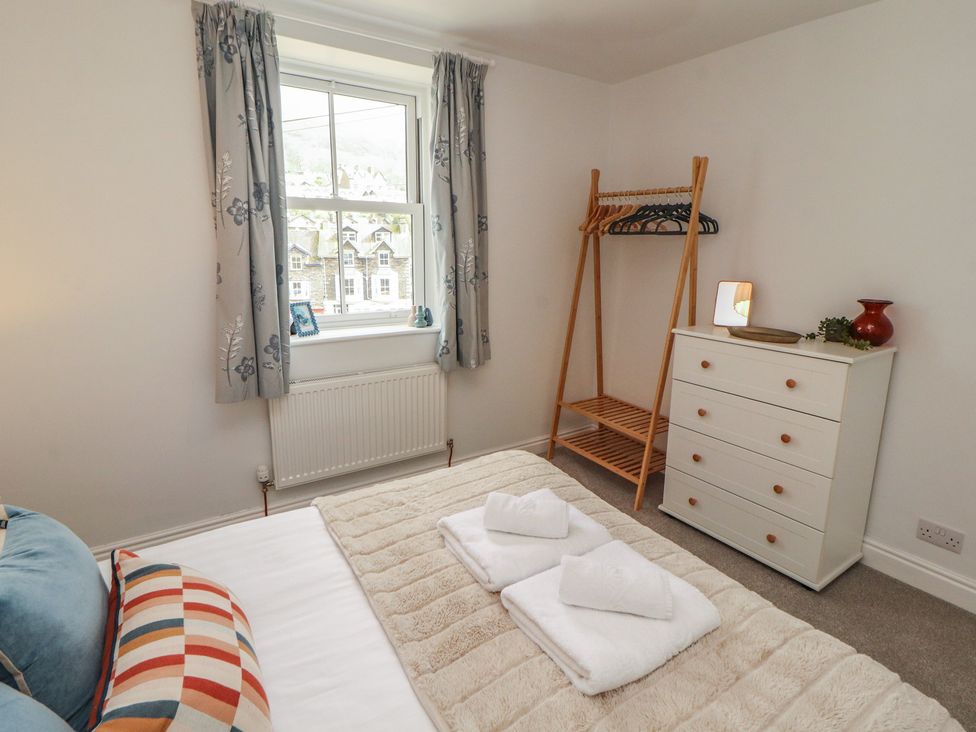 A bedroom with a bed and dressers at Rothay Cottage in Ambleside