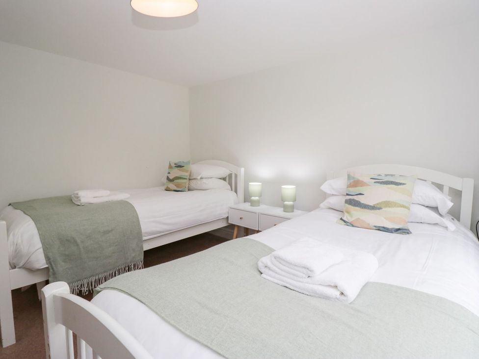 A bedroom with two beds and a side table at Rothay Cottage in Ambleside