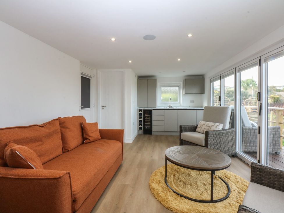 A living room with a sofa and kitchen area at The Bay in Benllech