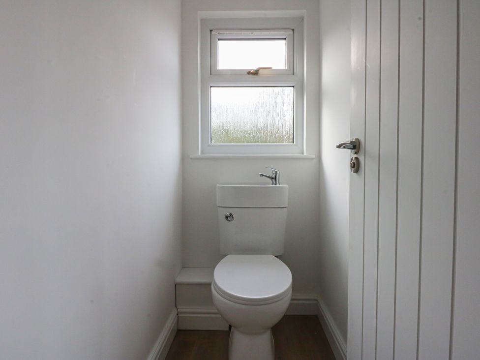 A bathroom with a toilet and window at The Bay in Benllech