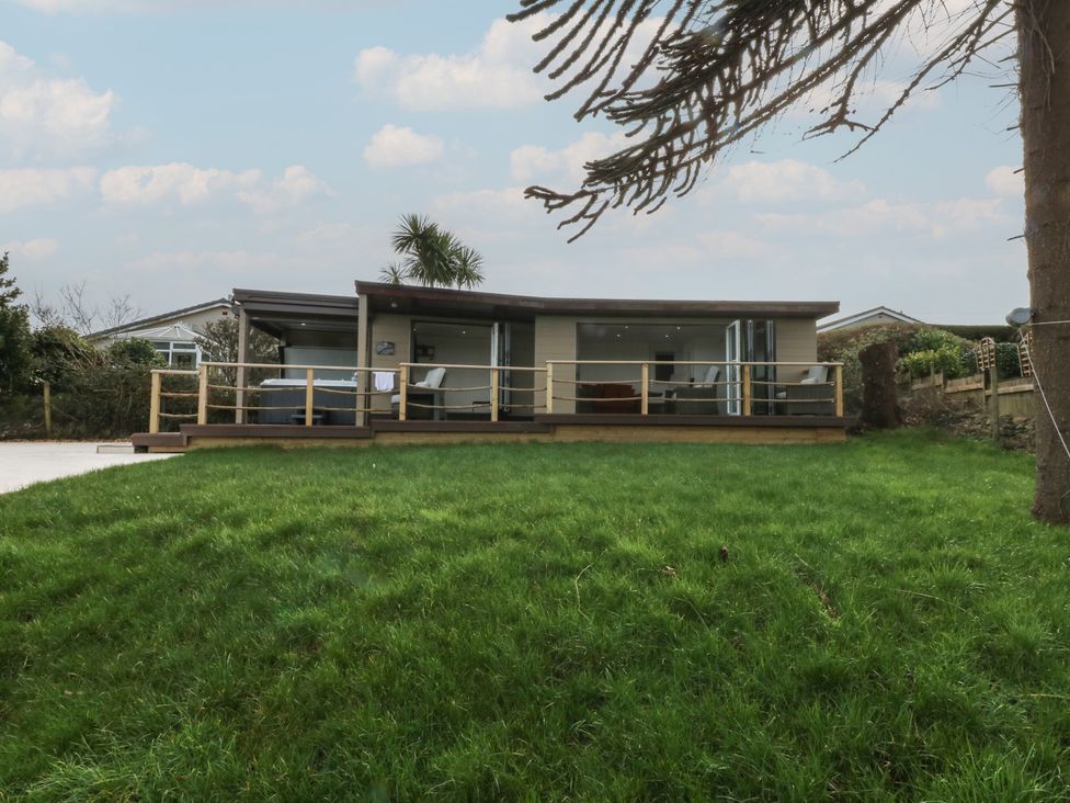 A house with a deck and grass in front at The Bay in Benllech