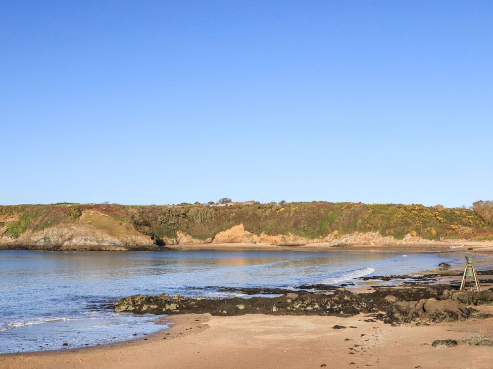 A beach with water and cliffs at Gwynlys in Cemaes Bay