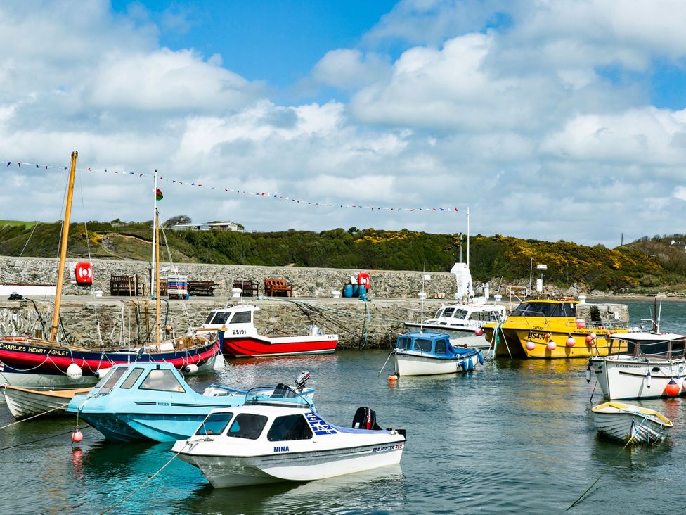 A harbor with various boats and a pier at Gwynlys in Cemaes Bay