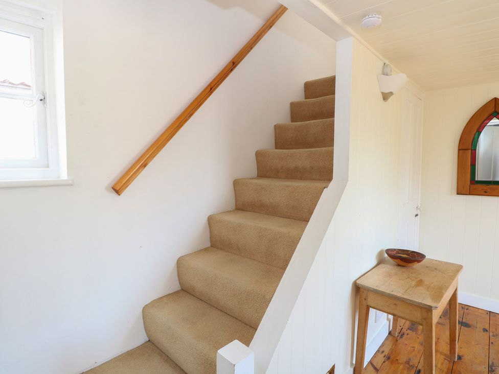 A staircase with a wooden table and window at Iona Cottage in Southwold