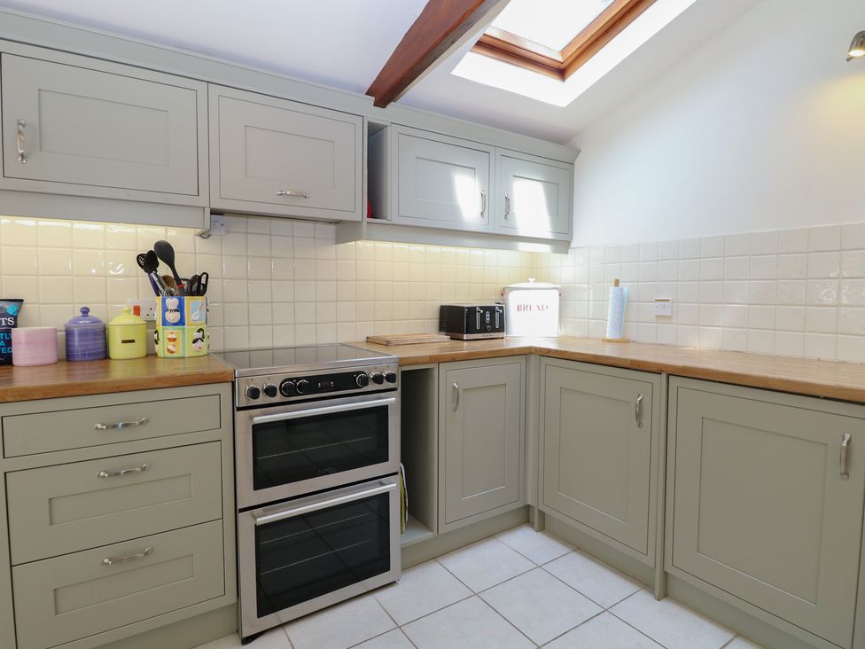 A kitchen with cabinets, a countertop, and an oven at Iona Cottage Southwold