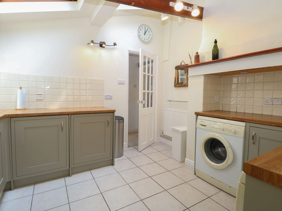 A laundry room with a washing machine and cabinets at Iona Cottage Southwold