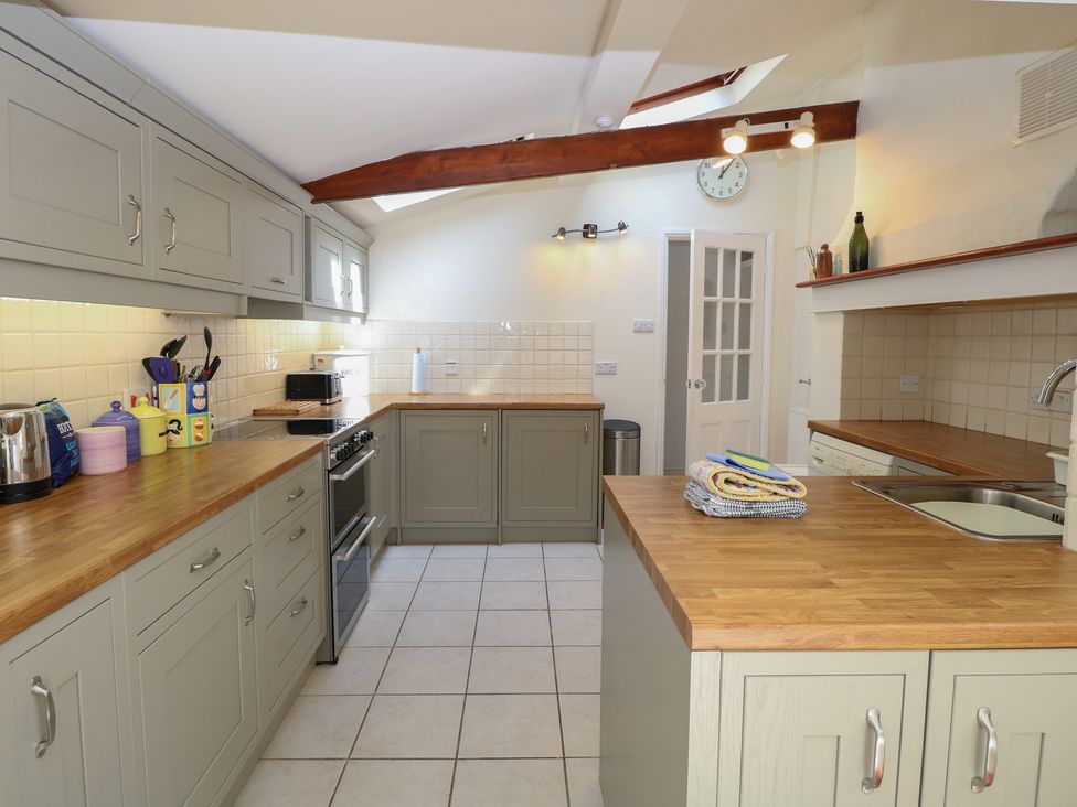 A kitchen with cabinets, countertops, and appliances at Iona Cottage Southwold