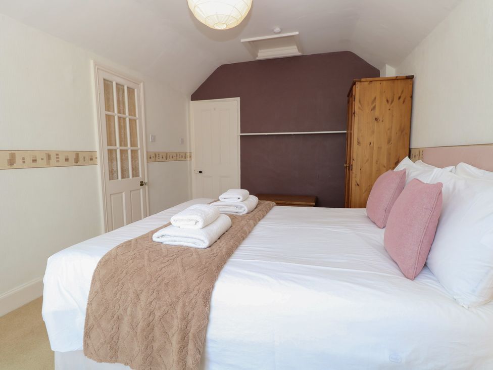 A bedroom with a bed and towels at Iona Cottage Southwold