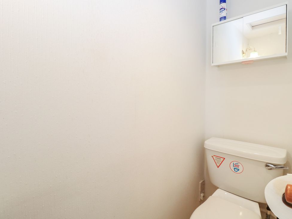 A bathroom with a toilet and a mirror at Iona Cottage in Southwold