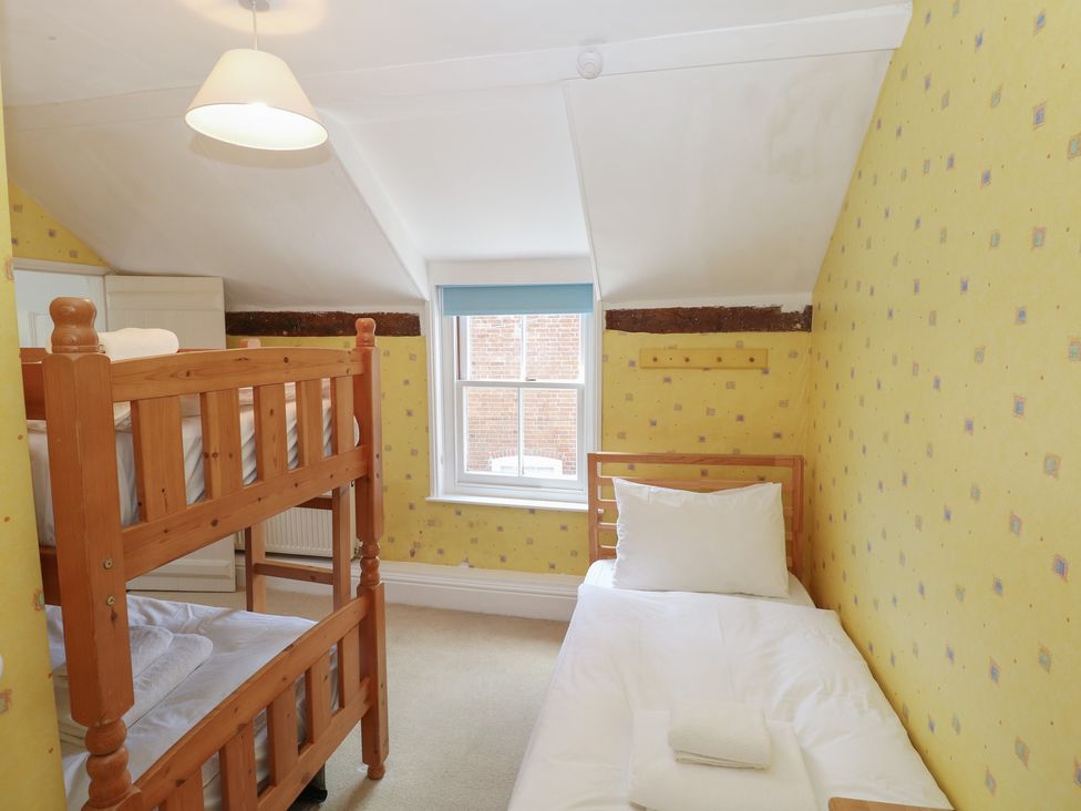 A bedroom with a bunk bed and a single bed at Iona Cottage in Southwold