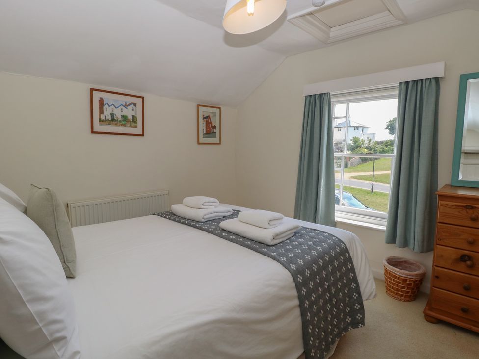A bedroom with a bed and framed art at Iona Cottage Southwold