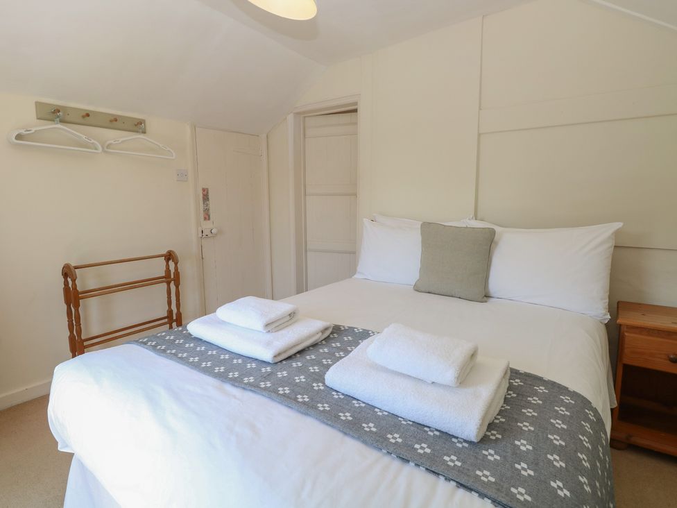 A bedroom with a bed and towels on display at Iona Cottage Southwold
