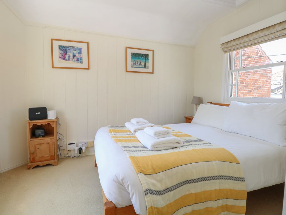 A bedroom with a double bed and nightstand at Iona Cottage Southwold