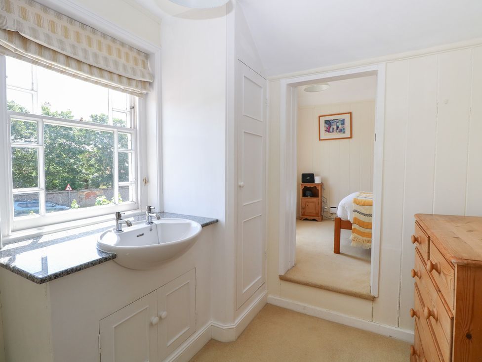 A bedroom with a sink and doorway leading to another room at Iona Cottage Southwold