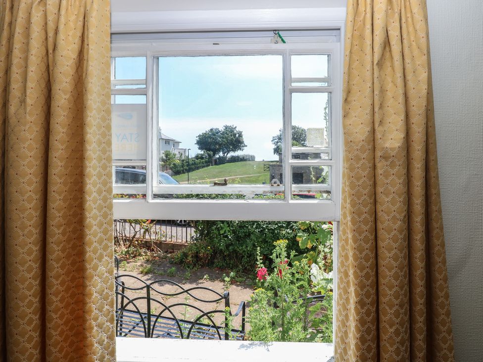 A window with curtains overlooking a garden at Iona Cottage Southwold