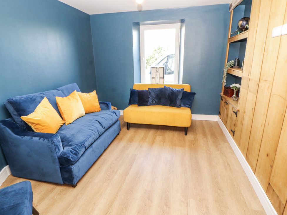 A living room with a blue sofa and yellow chair at 10 Keekle Terrace in Cleator Moor