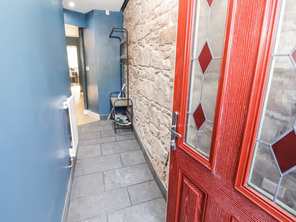A hallway with a red door and stone walls at 10 Keekle Terrace in Cleator Moor