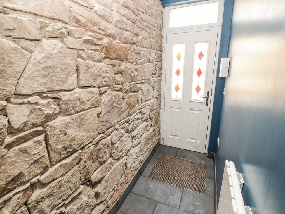 A hallway with a stone wall and white door at 10 Keekle Terrace Cleator Moor