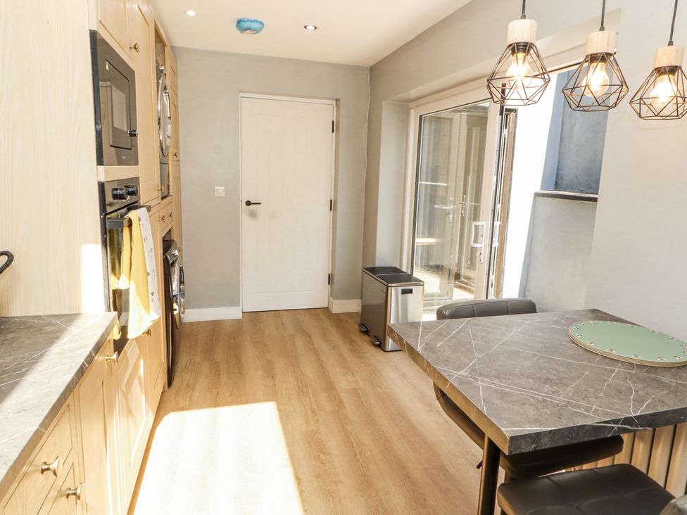 A kitchen with appliances and dining area at 10 Keekle Terrace in Cleator Moor