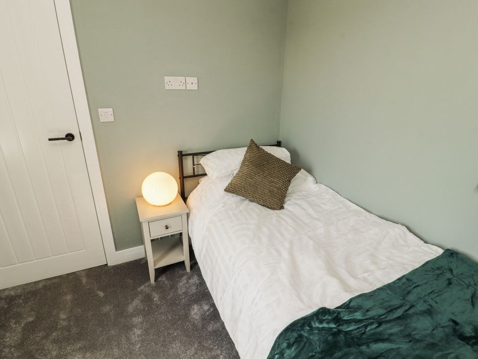 A bedroom with a single bed and a nightstand with a lamp at 10 Keekle Terrace Cleator Moor