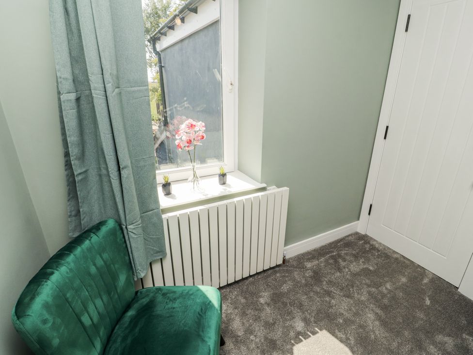A bedroom with a chair and a window at 10 Keekle Terrace in Cleator Moor