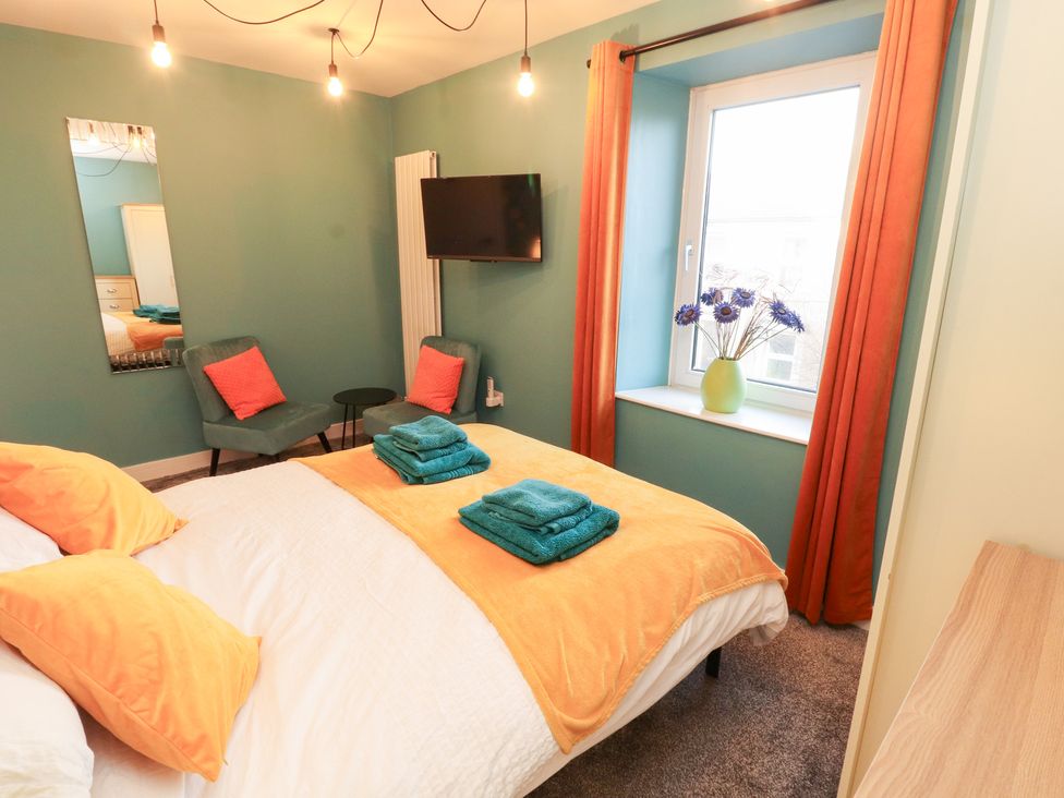 A bedroom with a bed and armchair at 10 Keekle Terrace in Keekle near Cleator Moor