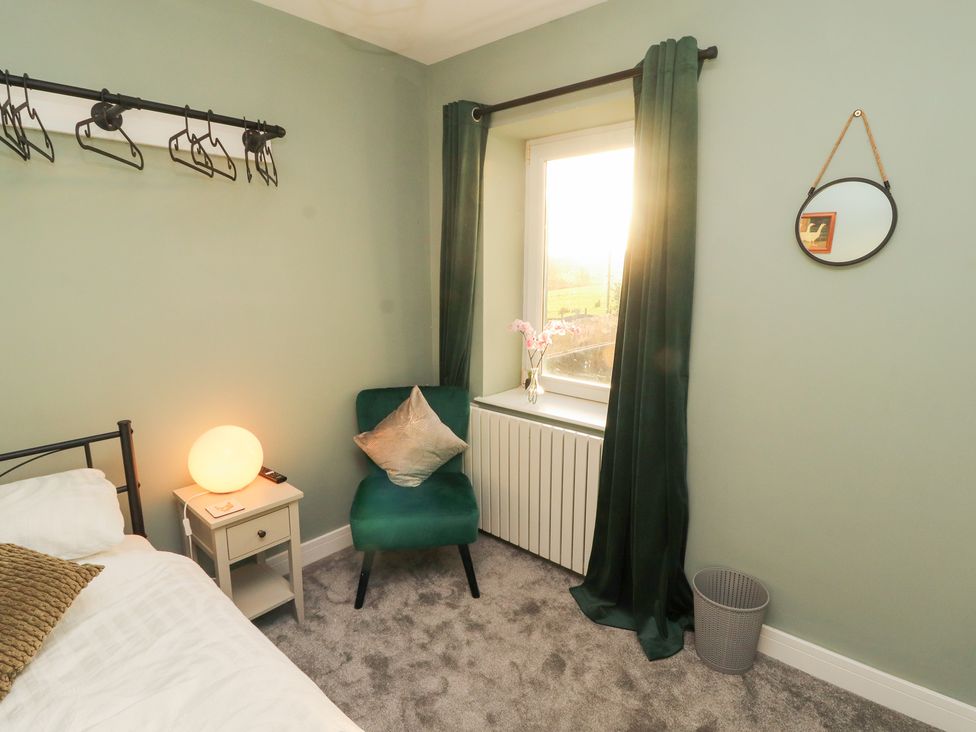 A bedroom featuring a bed, side table, chair and window at 10 Keekle Terrace Keekle near Cleator Moor