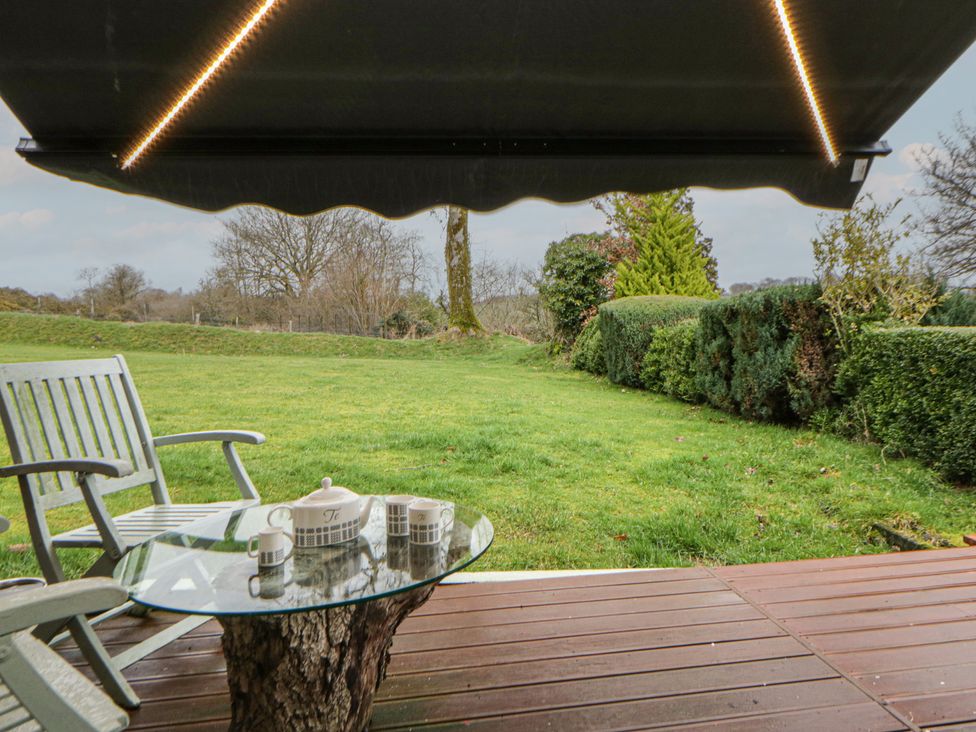 A garden with a table and chairs under an awning at The Old Workshop in Dre-Fach near Lampeter