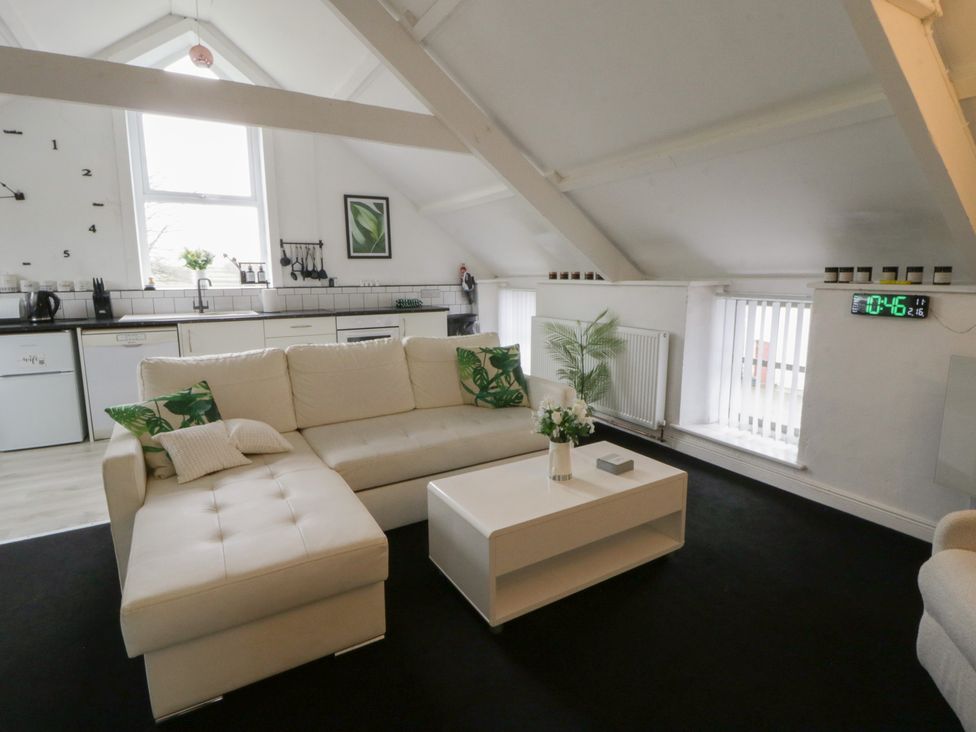 A living room with a sofa and kitchen area at The Old Workshop in Dre-Fach near Lampeter