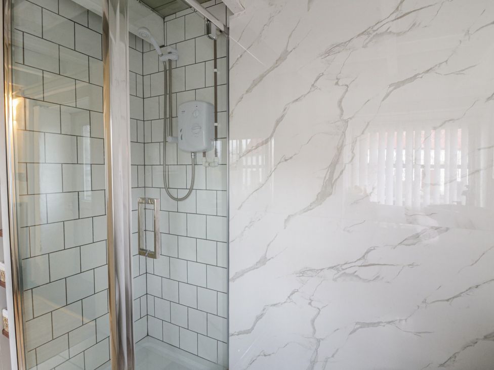 A shower with glass door and wall tiles at The Old Workshop in Dre-Fach near Lampeter