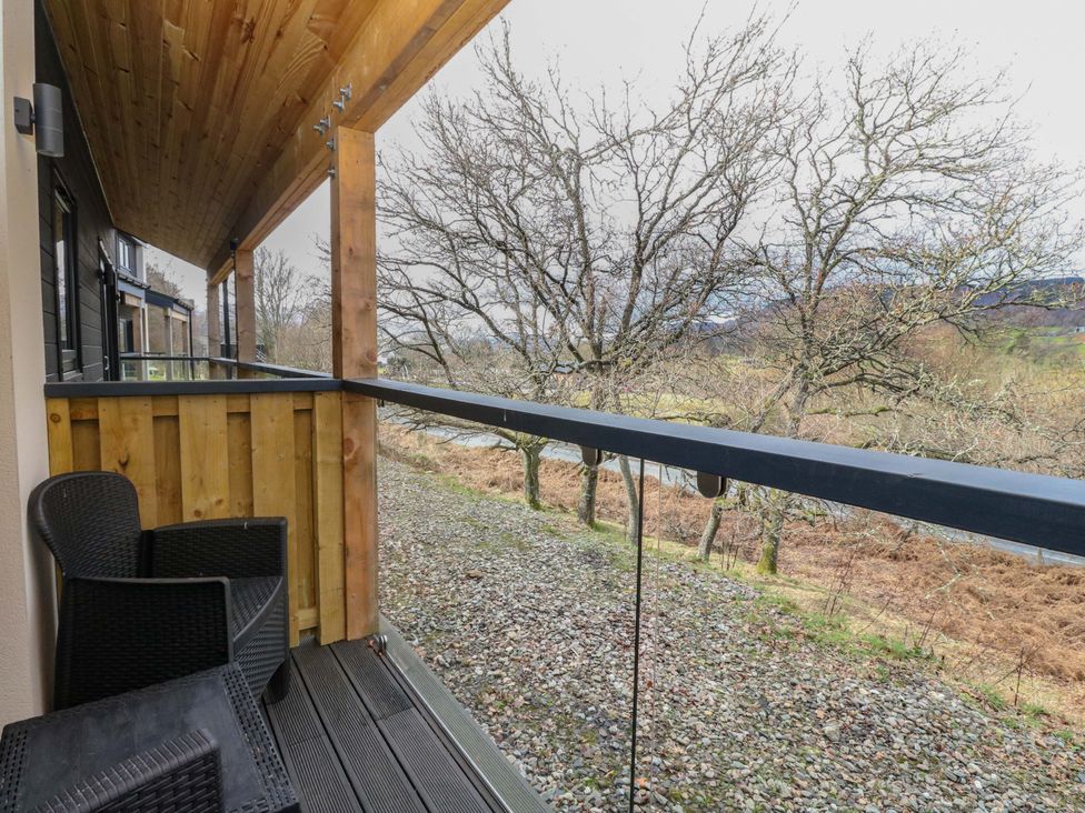 A balcony with a chair overlooking trees at 25 Strathtay Lodges in Aberfeldy