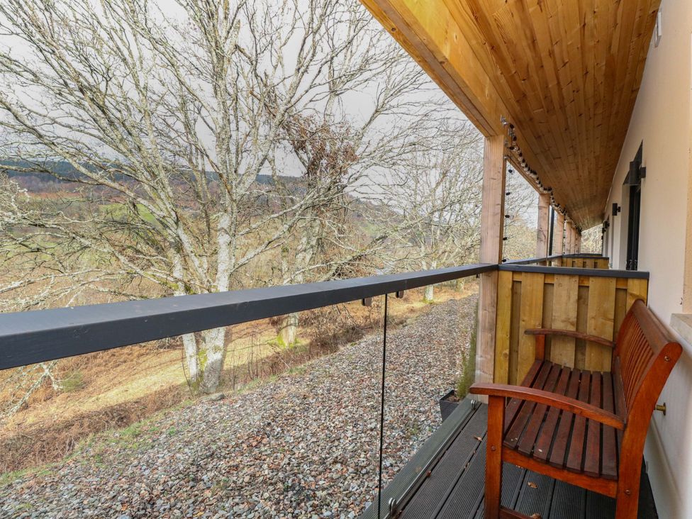 A balcony with a wooden bench and gravel area at 25 Strathtay Lodges in Aberfeldy