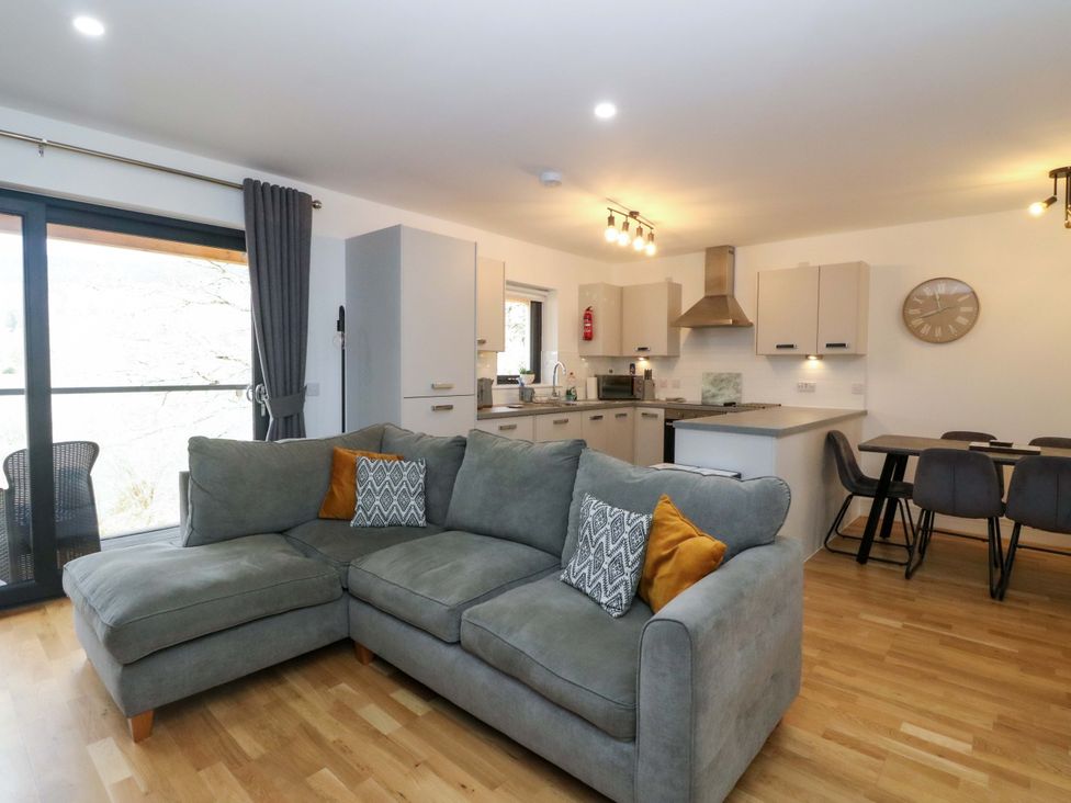 A living room with a sofa and kitchen area at 25 Strathtay Lodges in Aberfeldy