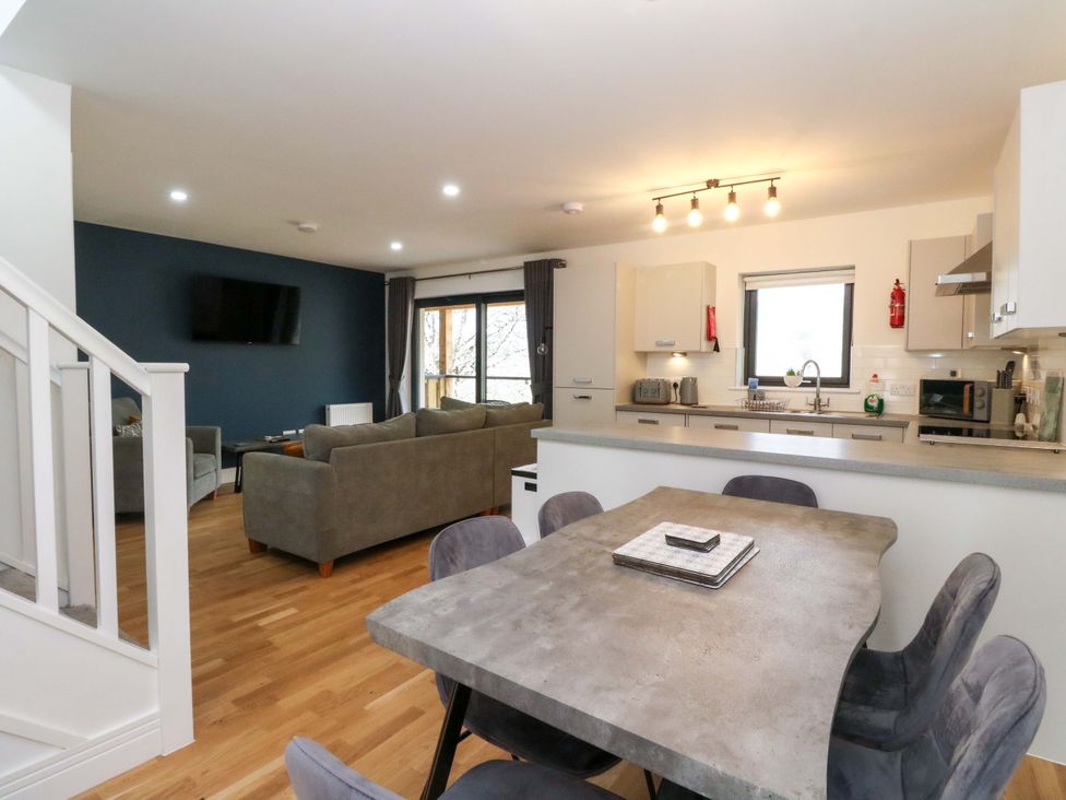 A living room with a television and kitchen area at 25 Strathtay Lodges in Aberfeldy